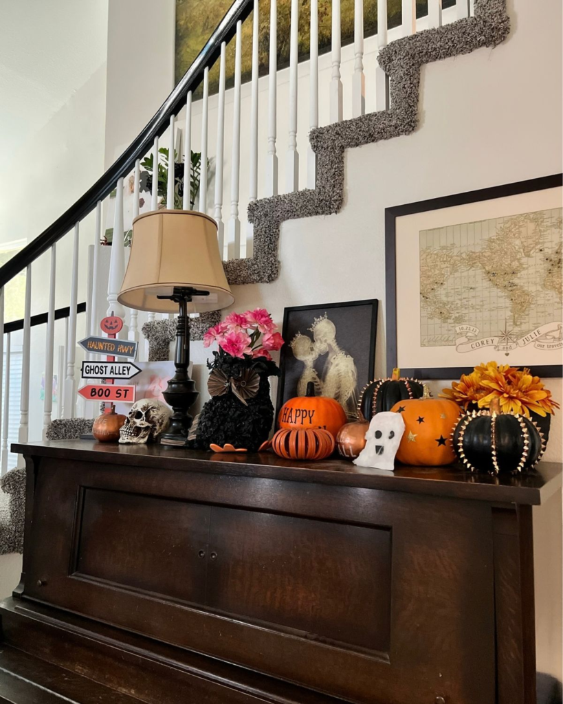 Fall and Halloween decorations displayed on a console table inside a home