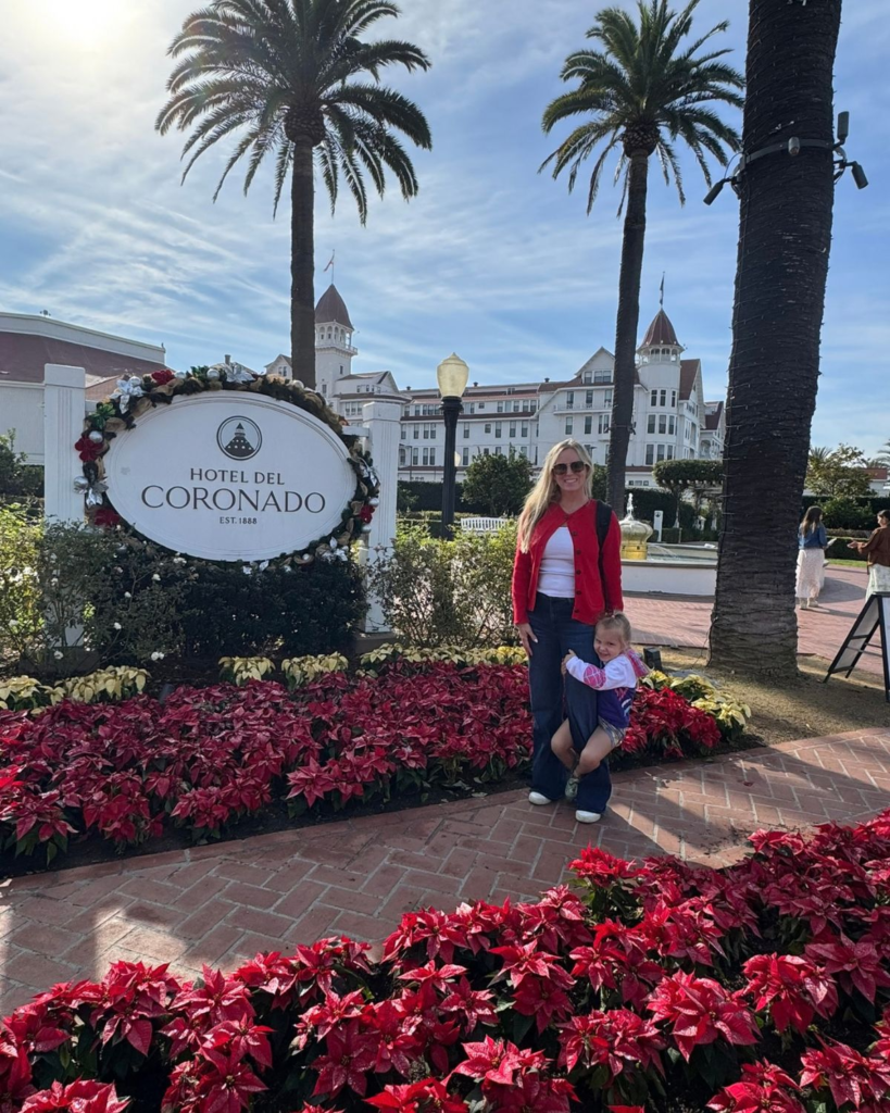 Hotel Del Coronado entrance sign decorated with holiday garlands and surrounded by poinsettias