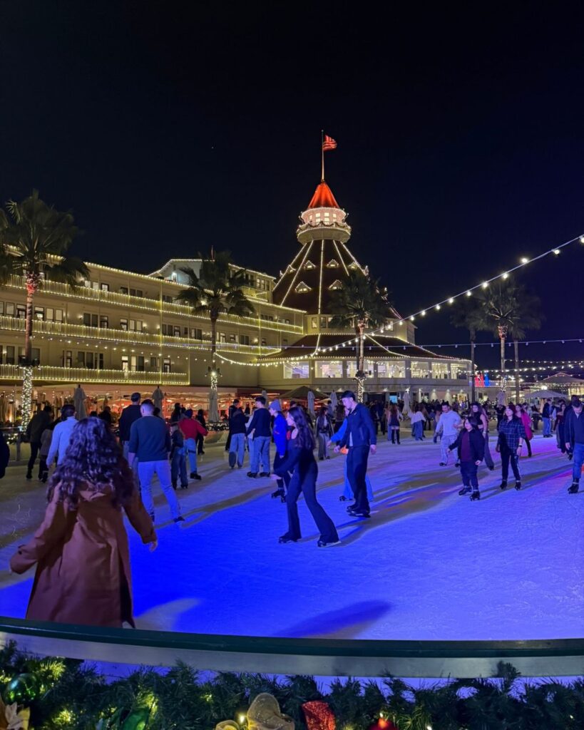 Guests ice skating at night in front of the illuminated Hotel Del Coronado