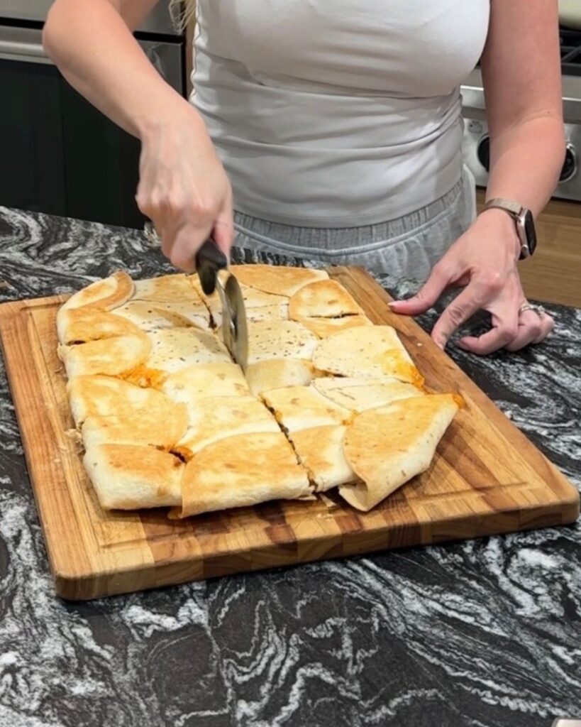 Sheet pan crunchwrap being cut into individual servings on a wooden cutting board