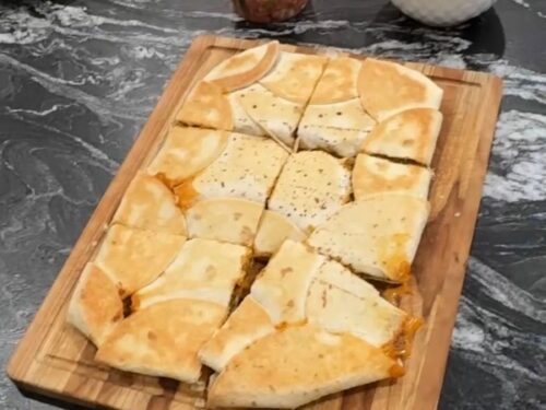 Baked sheet pan crunchwrap cut into squares on a wooden serving board