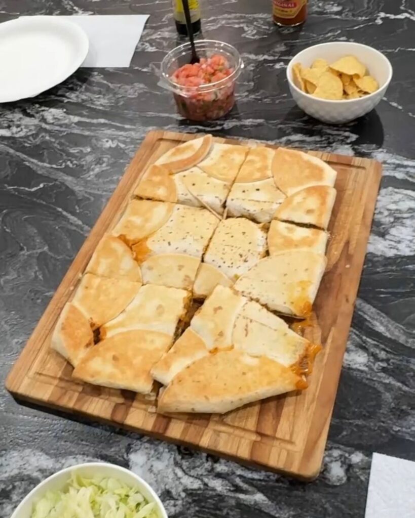 Baked sheet pan crunchwrap cut into squares on a wooden serving board