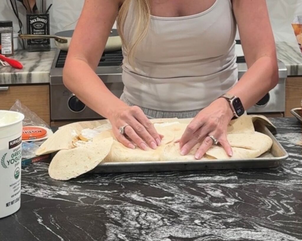 Tortillas being folded over the filling to close a sheet pan crunchwrap