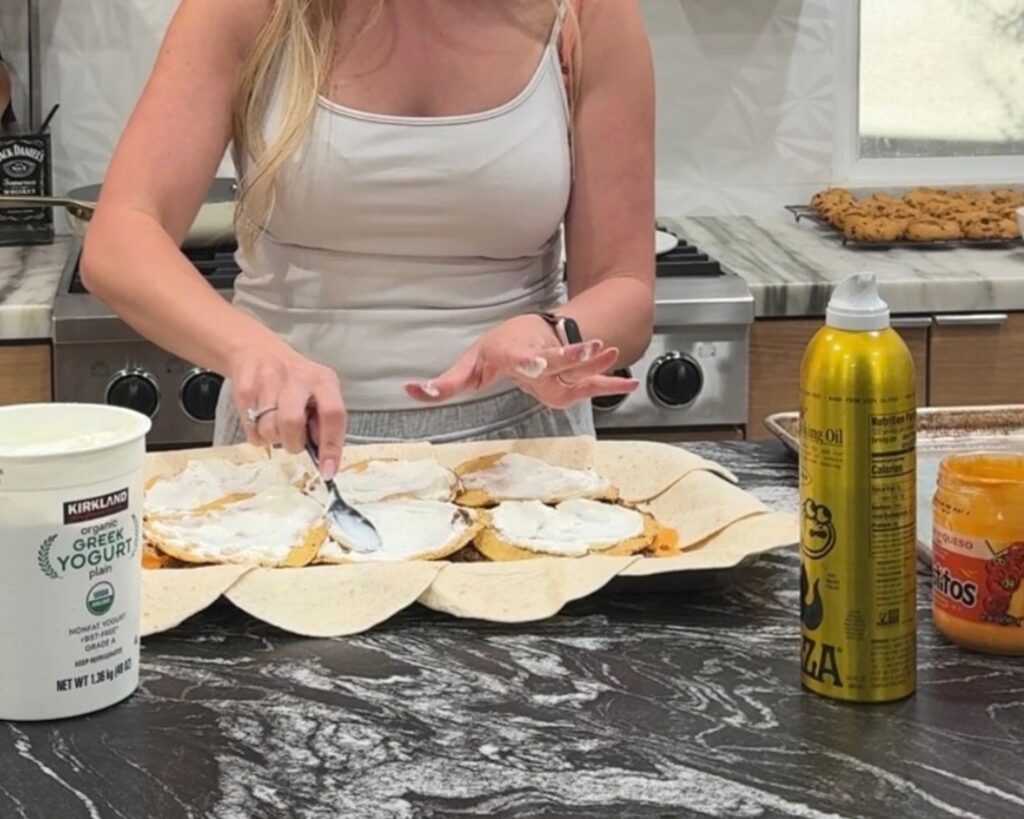 Greek yogurt being spread over the crunchwrap filling before baking
