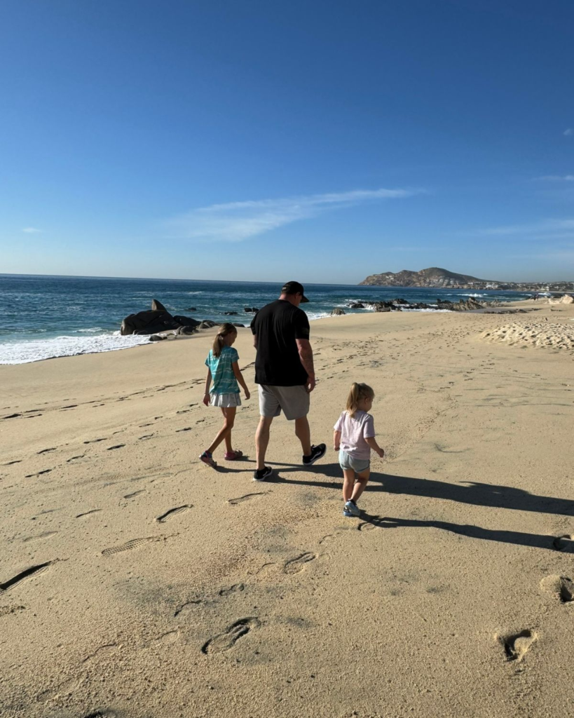 Dad and daughter walking along the beach in Cabo
