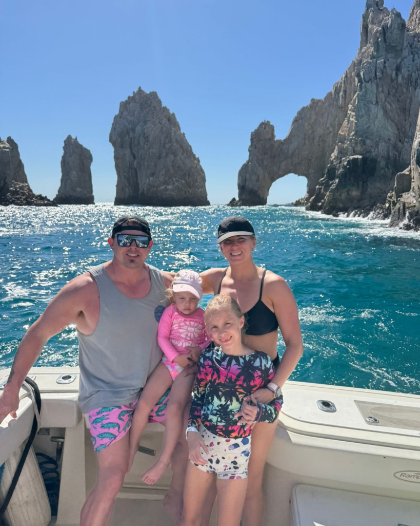 Family posing on a boat near the Arch of Cabo San Lucas