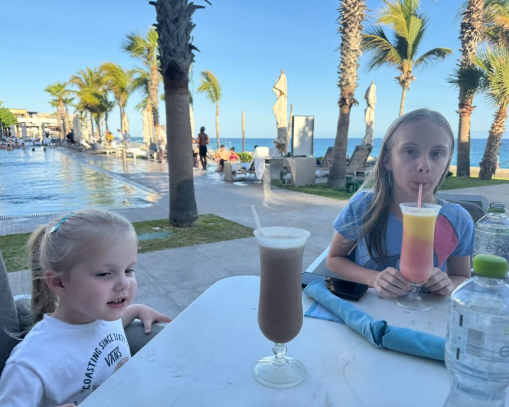 Two young girls drinking milkshakes by the pool
