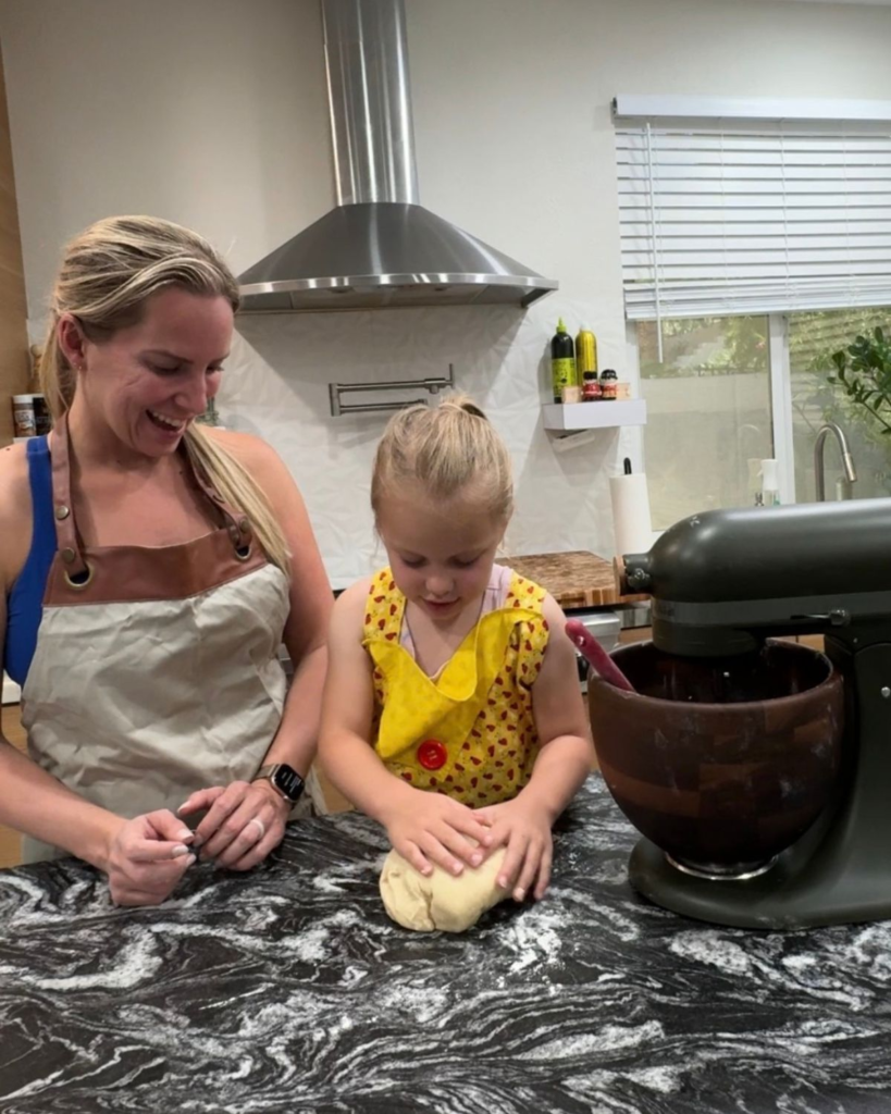 Mom and young daughter making homemade cinnamon rolls together in the kitchen