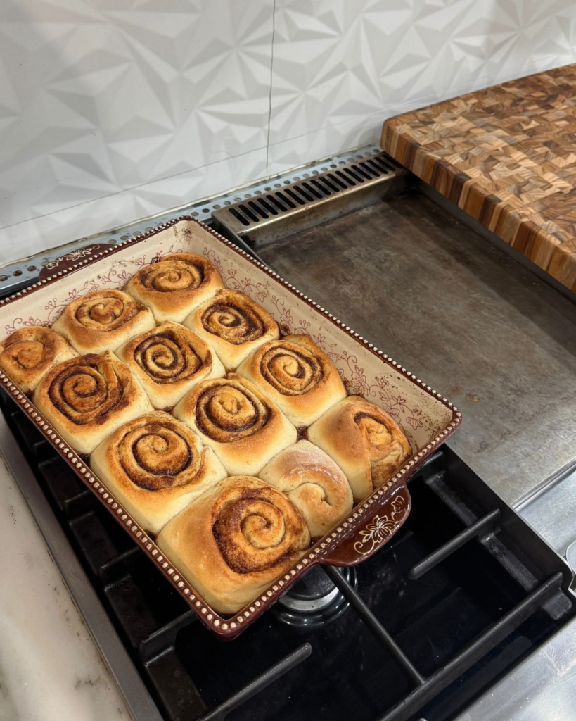 Freshly baked cinnamon rolls in a baking dish on the stovetop