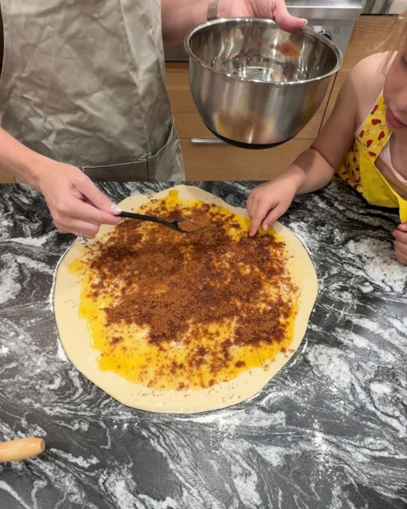 Spreading cinnamon and brown sugar filling over rolled-out dough