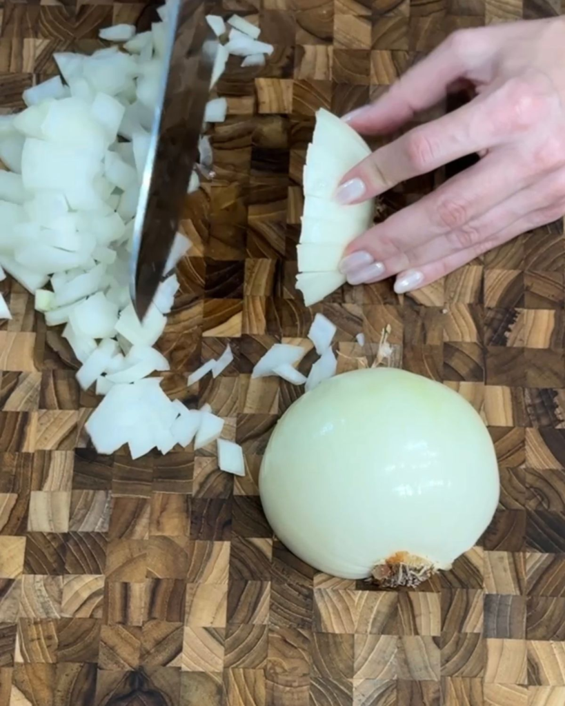 Diced white onion on a wooden cutting board