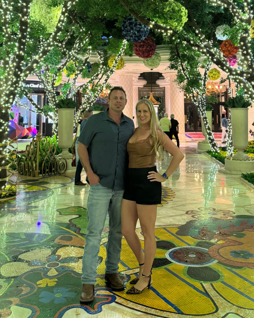 Julie and Corey standing together in a landscaped courtyard at Wynn Las Vegas